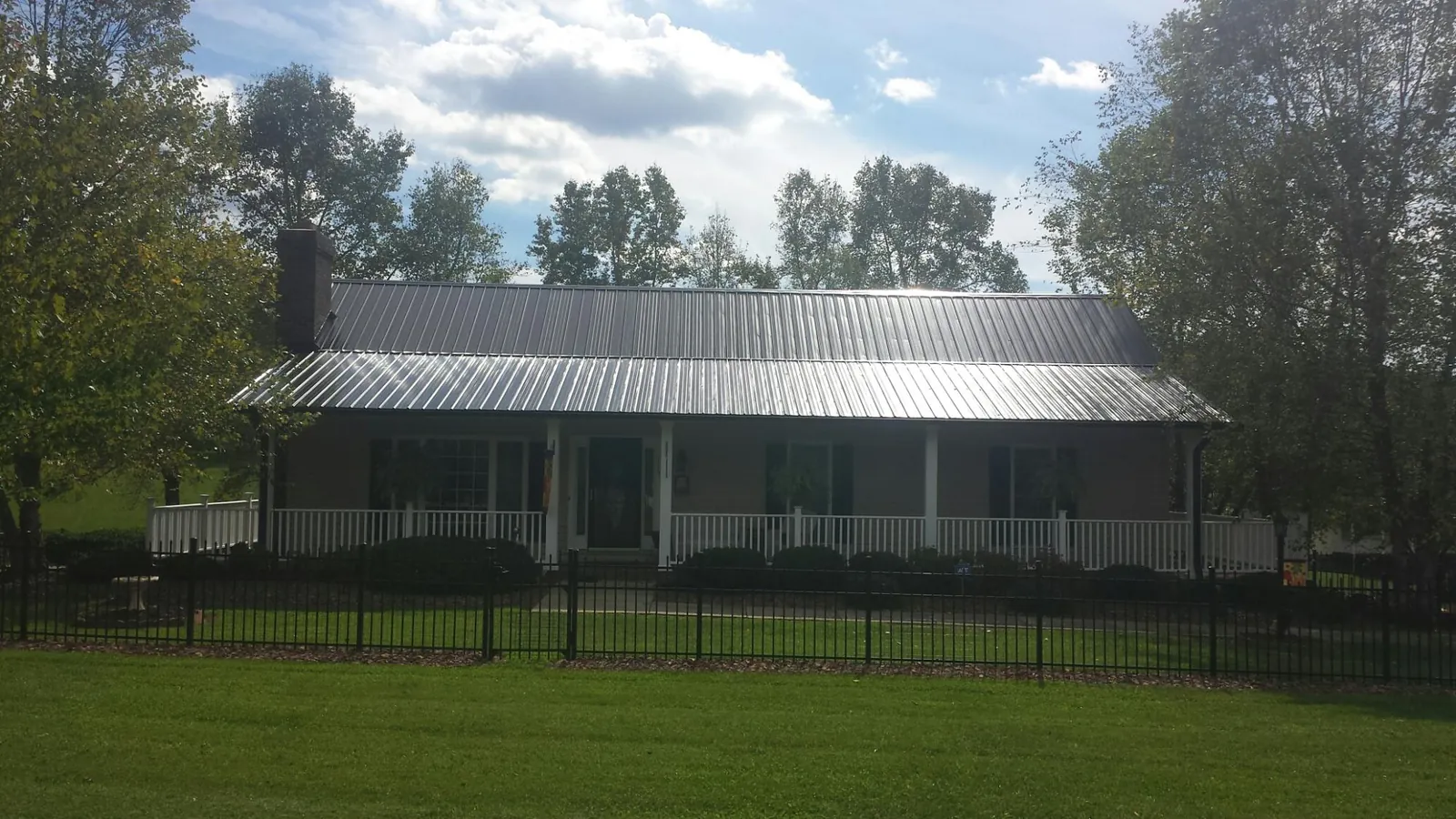 Gray metal roof on a brick ranch with a full width front porch — Gutter Guard Installation work by our crew in Catawissa