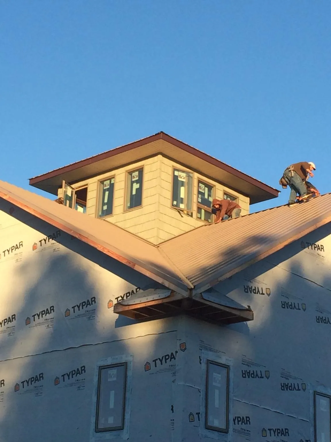 Roofers working around a rooftop cupola on a new metal roof at sunset — Roof Waterproofing in Catawissa by Roofing Brothers